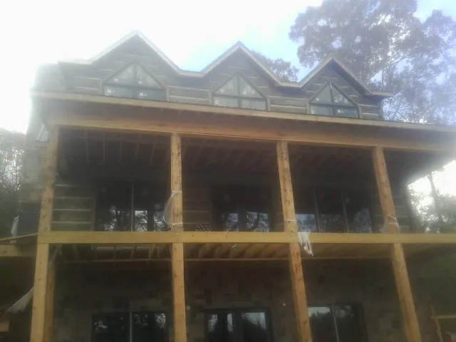 Dormers and porch framing on a large log home under construction — Roof Coating work by our crew in Chimney Rock