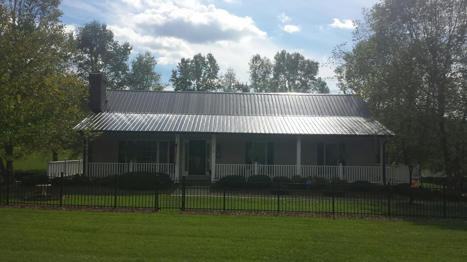Gray metal roof on a brick ranch with a full width front porch — Gutter Guard Installation work by our crew in Chimney Rock