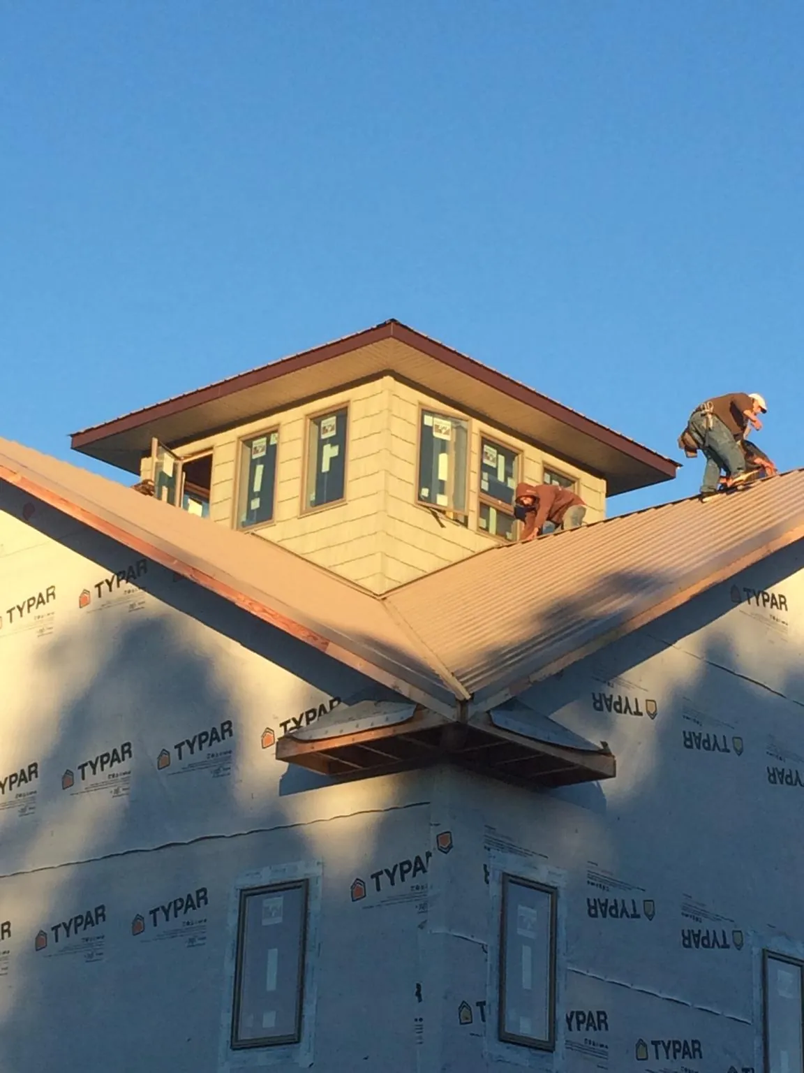 Roofers working around a rooftop cupola on a new metal roof at sunset — Roof Waterproofing in Chimney Rock by Roofing Brothers